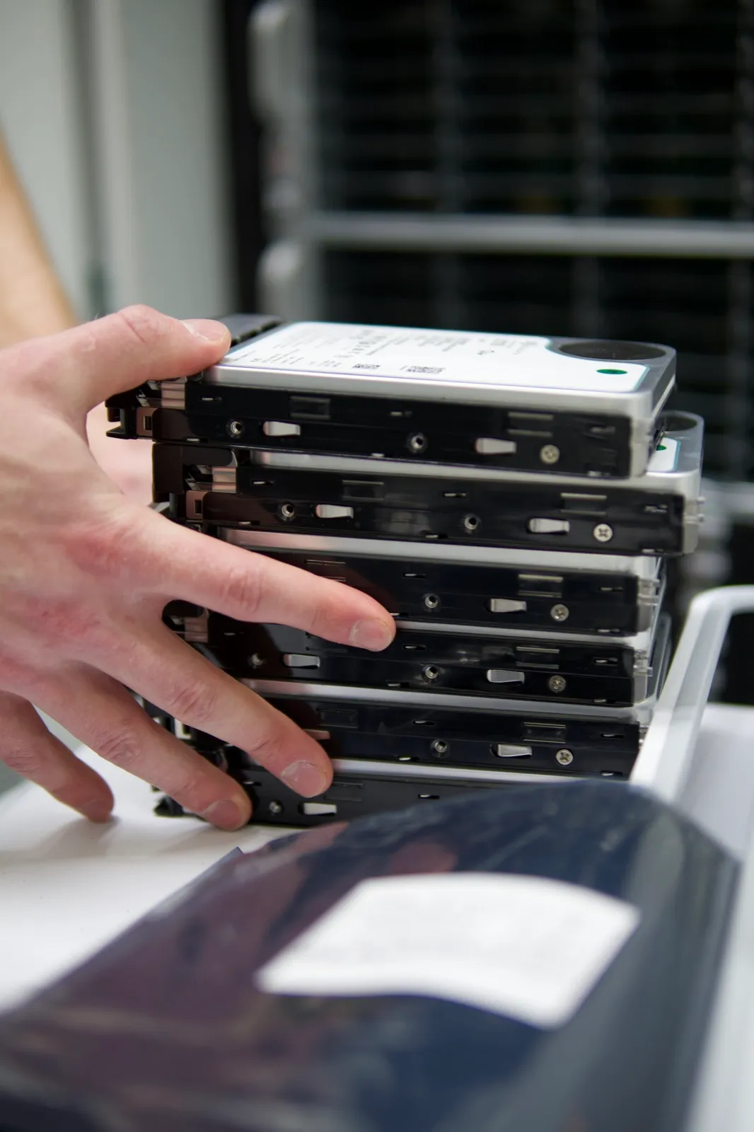 A stack of removed hard drives being handled for secure data destruction