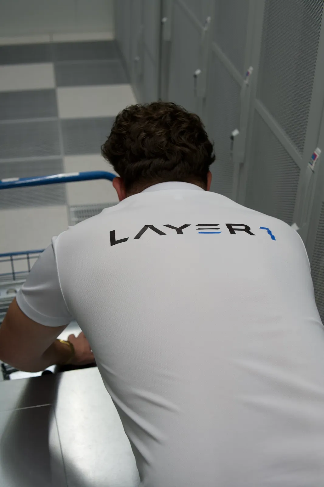 Layer One engineer in a branded polo working hands-on at datacenter hardware