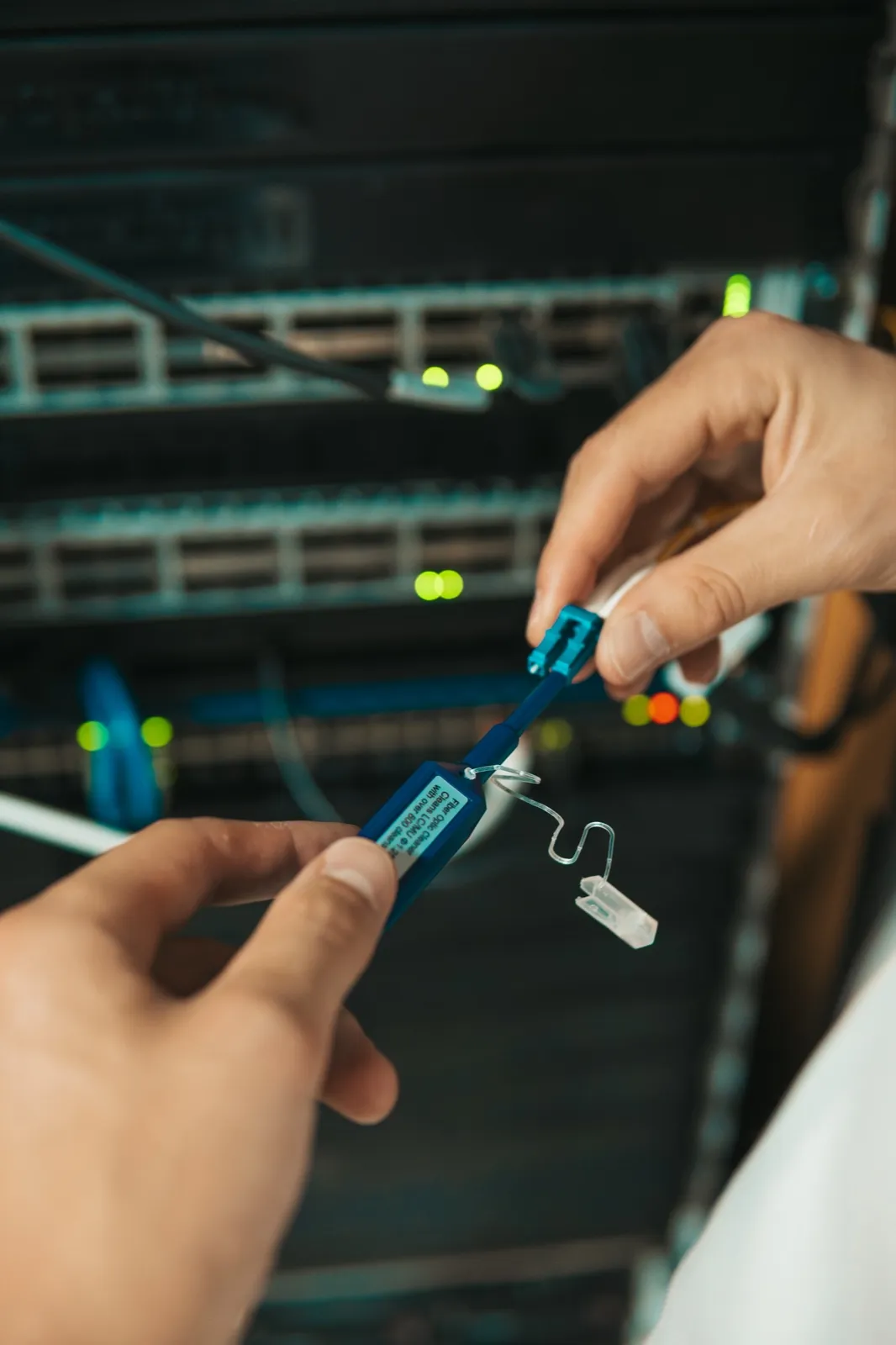 Close-up of a labeled fiber connector being handled at a switch