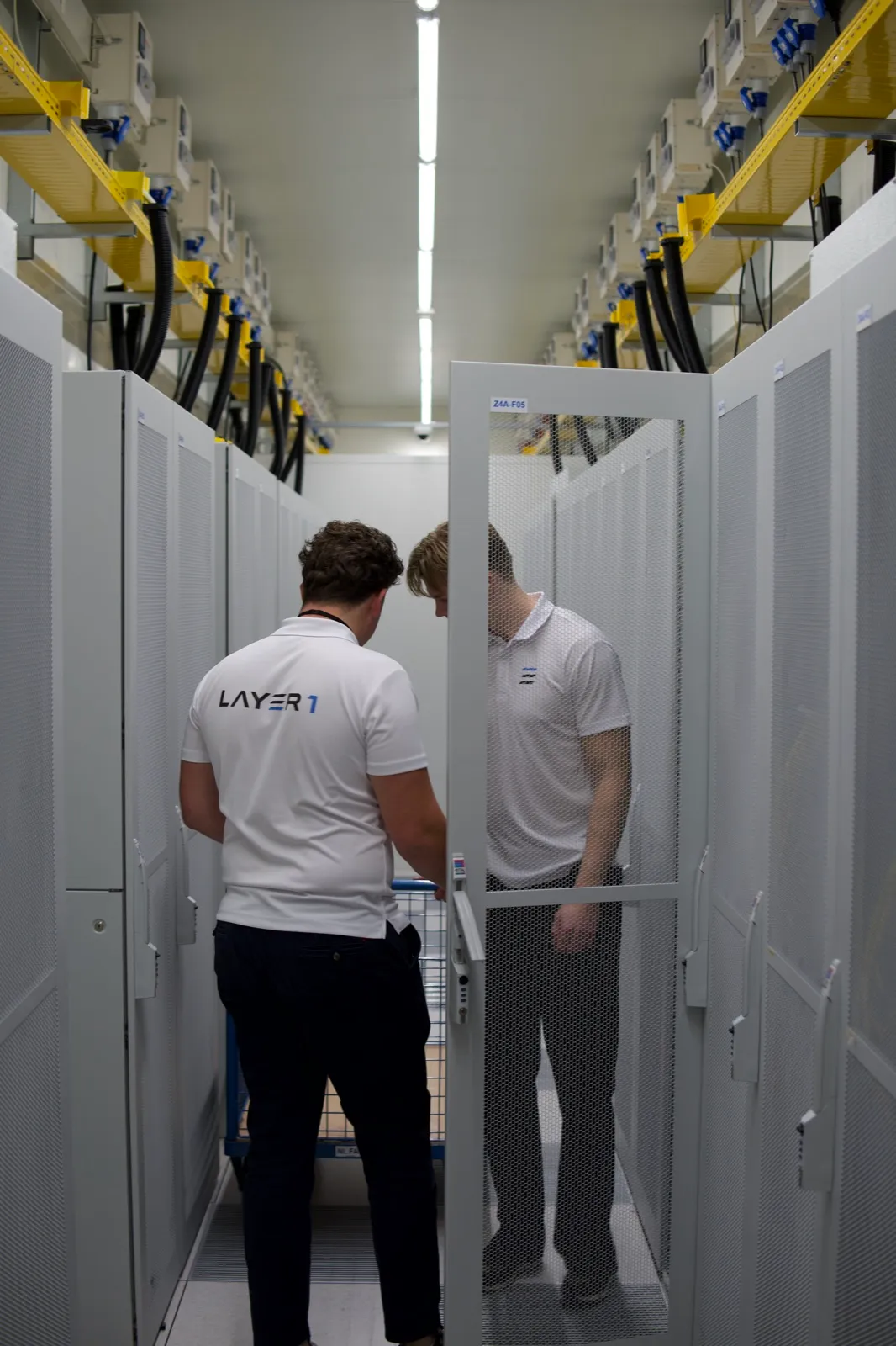 Two Layer One engineers working at racks in a datacenter aisle